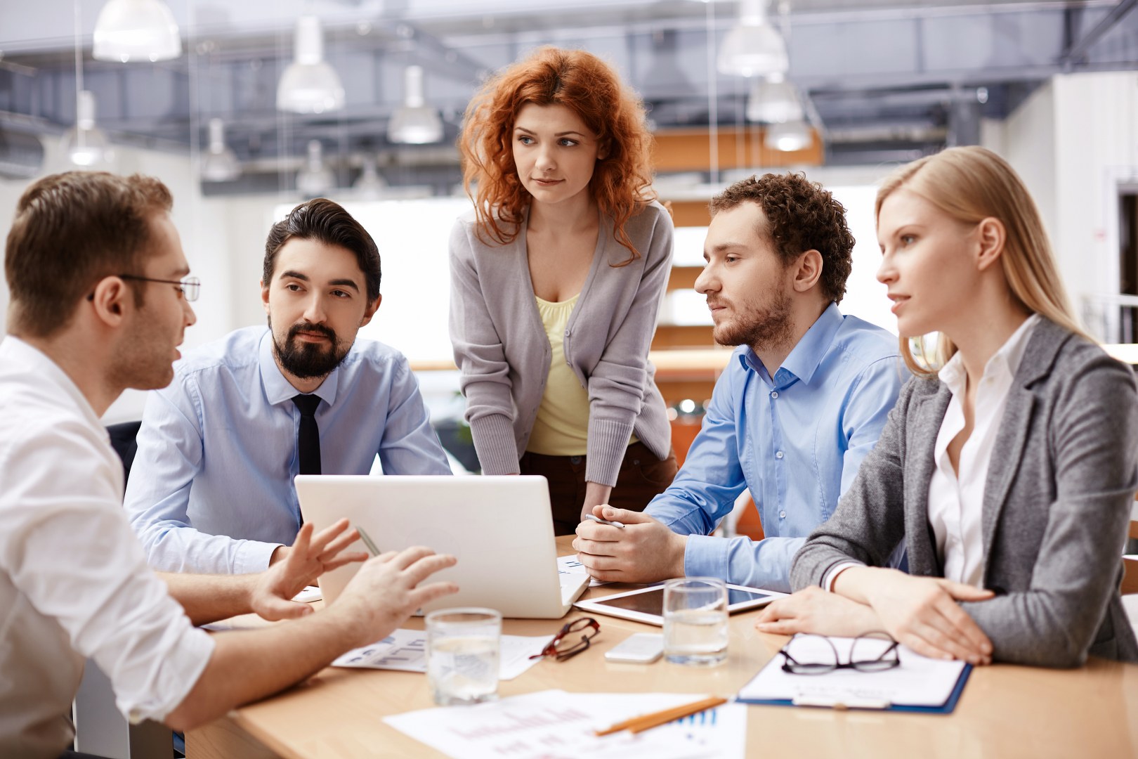 Group of business partners listening to colleague at meeting