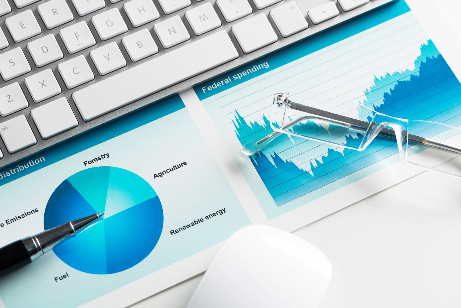 Business workplace with keyboard mouse and papers with graphs and diagrams